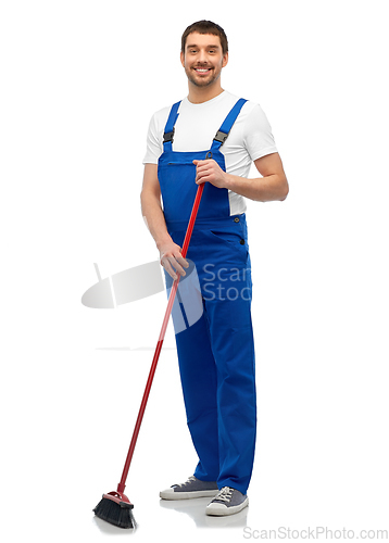 Image of male cleaner in overall cleaning floor with broom