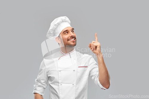 Image of happy smiling male chef pointing finger up