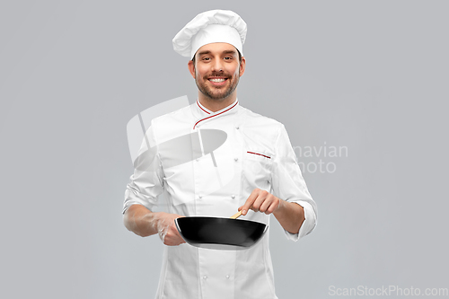 Image of smiling male chef with frying pan cooking food