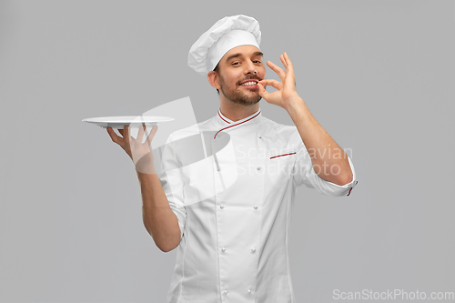 Image of happy smiling male chef holding empty plate