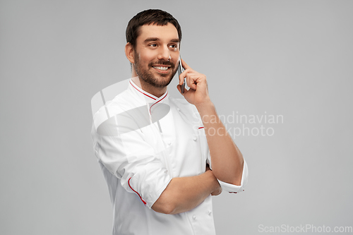 Image of happy smiling male chef calling on smartphone