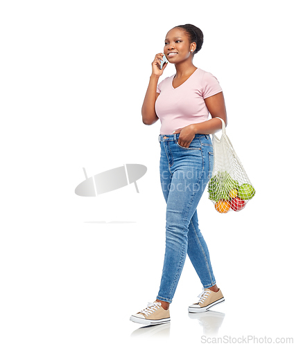 Image of woman with food in net bag calling on smartphone