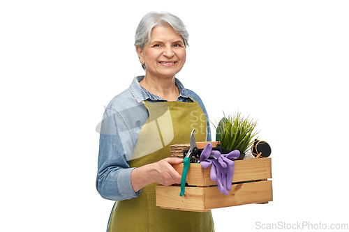 Image of smiling senior woman with garden tools in box