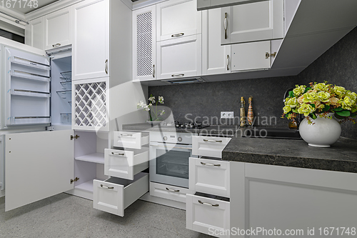 Image of Open doors and drawers open at modern white kitchen