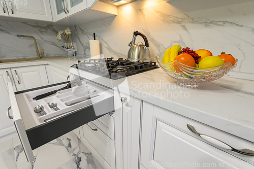 Image of Open drawers with kitchenware at modern white kitchen