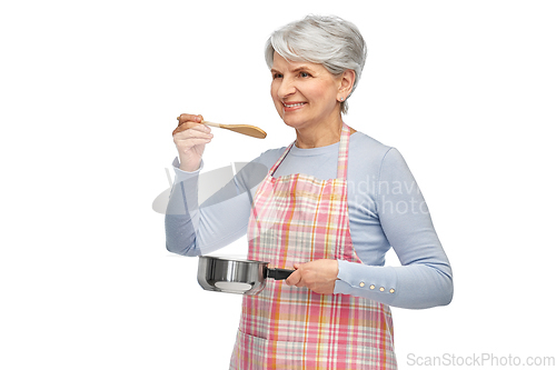 Image of senior woman in apron with pot cooking food