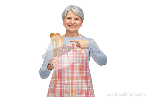 Image of smiling senior woman in apron with wooden spoons