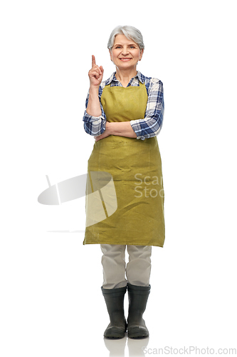 Image of happy old woman in garden apron pointing finger up