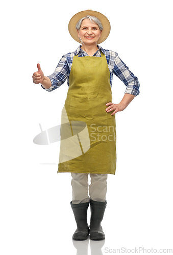 Image of senior woman in garden apron showing thumbs up