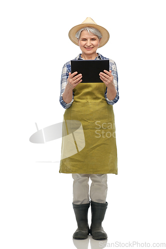 Image of happy senior woman in garden apron with tablet pc