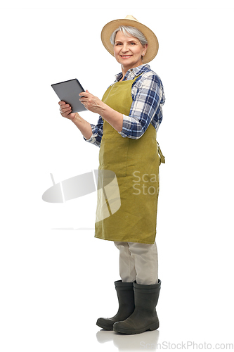 Image of happy senior woman in garden apron with tablet pc