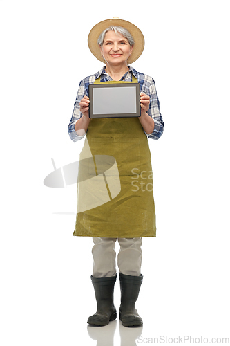 Image of happy senior woman in garden apron with tablet pc