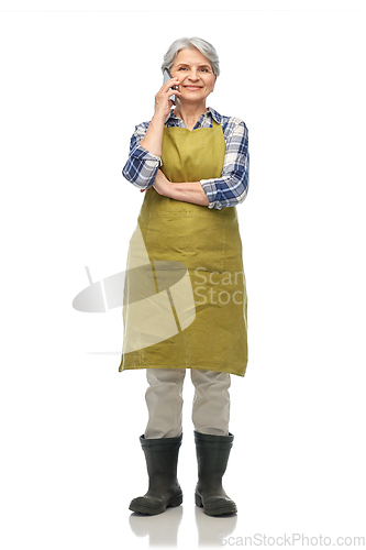 Image of senior woman in garden apron calling on smartphone