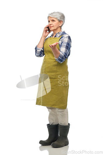 Image of senior woman in garden apron calling on smartphone