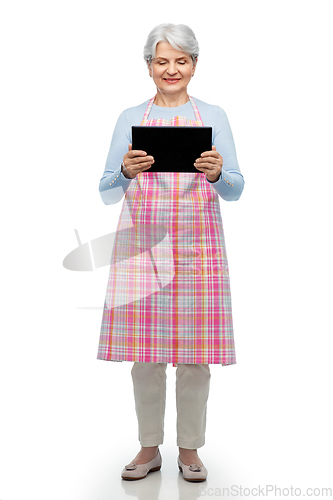 Image of smiling senior woman in apron with tablet computer