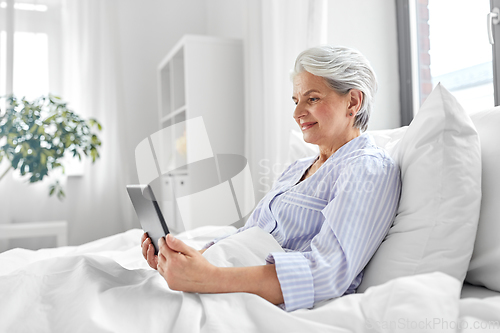 Image of senior woman with tablet pc in bed at home bedroom