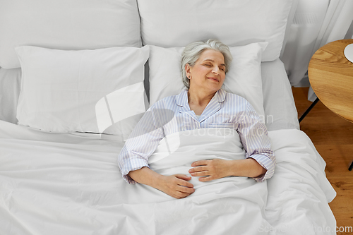 Image of happy senior woman sleeping in bed at home bedroom