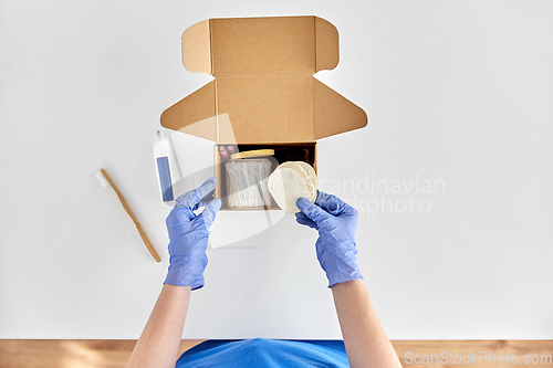 Image of hands in gloves packing parcel box with cosmetics