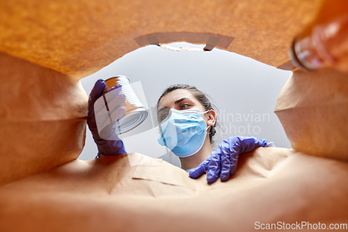 Image of woman in gloves and mask with food in paper bag