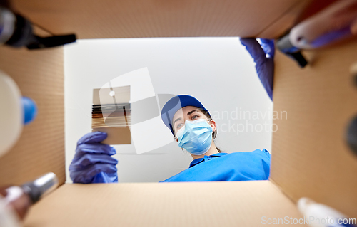 Image of woman in mask packing hair bands to parcel box