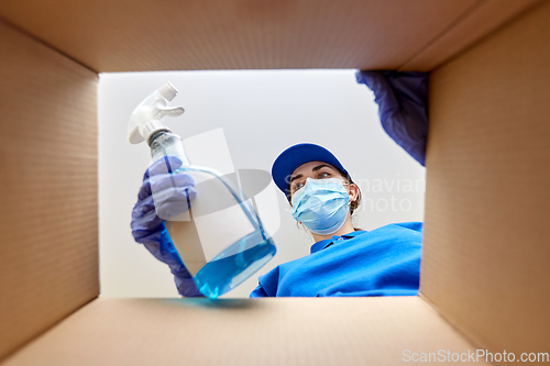 Image of woman in mask packing cleaning supplies in box