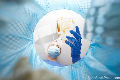 Image of doctor throwing plastic container into trash can