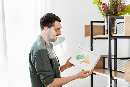 Image of man decorating home with picture in frame