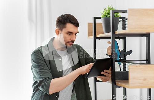 Image of man with tablet pc at shelf at home