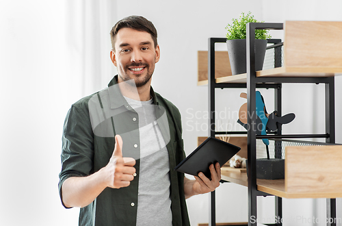 Image of happy smiling man with tablet pc at shelf at home