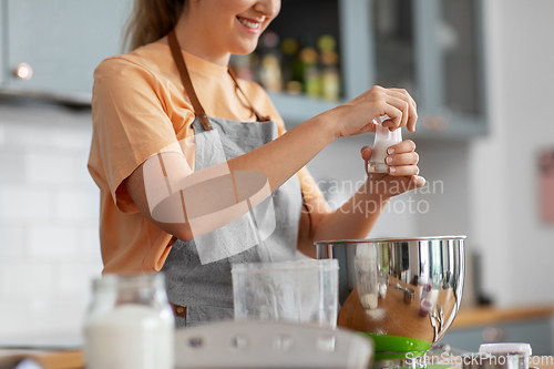Image of happy young woman cooking food on kitchen at home