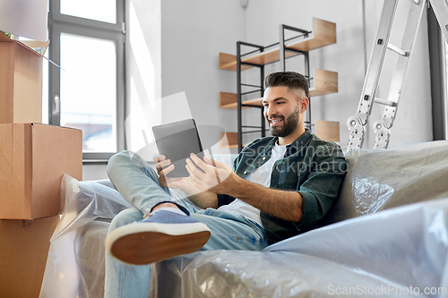 Image of man with tablet pc and boxes moving into new home