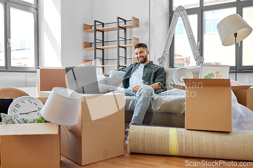 Image of man with laptop computer and moving into new home