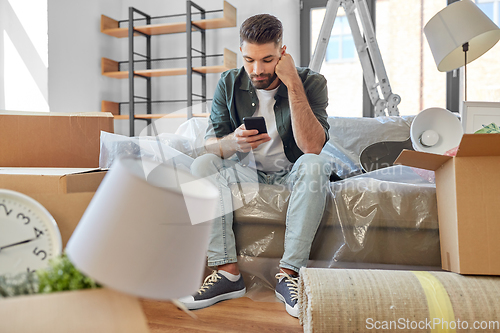 Image of sad man with smartphone and boxes moving home