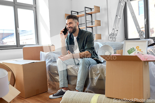 Image of happy man calling on smartphone moving to new home
