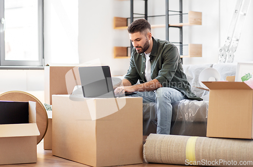 Image of man with laptop computer and moving into new home
