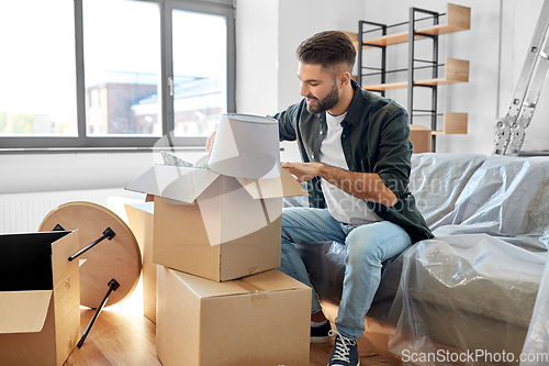 Image of happy man unpacking boxes and moving to new home