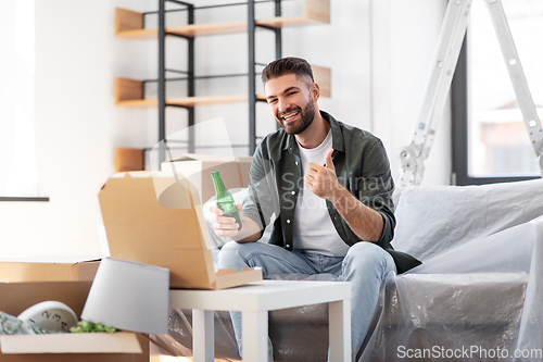 Image of man with box of pizza and beer bottle at new home