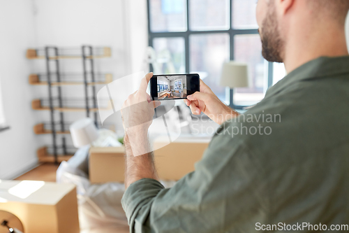 Image of man with smartphone taking picture of new home