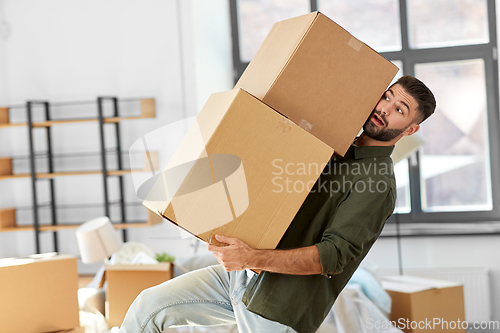 Image of man holding heavy boxes and moving to new home