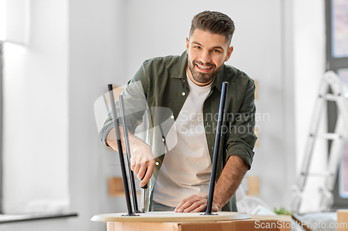 Image of happy man assembling coffee table at new home