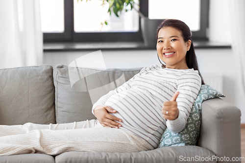 Image of happy pregnant asian woman showing thumbs up