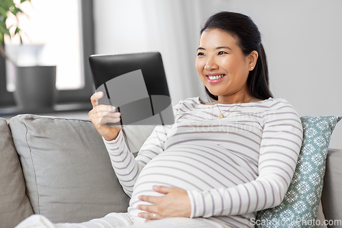 Image of happy pregnant asian woman with tablet pc at home