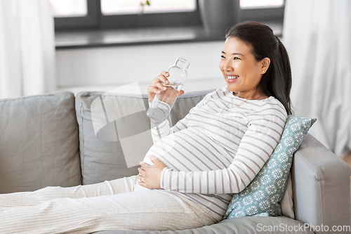 Image of pregnant woman with water in glass bottle at home
