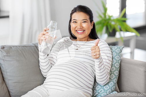 Image of pregnant woman with water in glass bottle at home