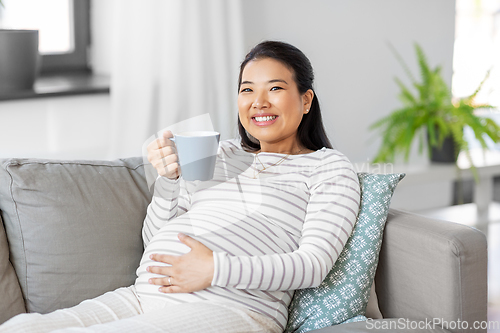 Image of happy pregnant woman drinking tea at home