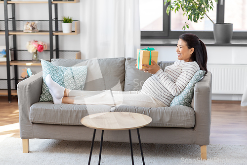 Image of happy pregnant woman with gift box at home