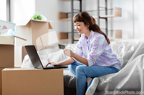 Image of woman with laptop and credit card at new home