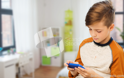 Image of boy with smartphone texting or playing at home