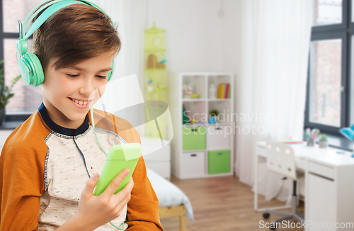 Image of happy boy with smartphone and headphones at home