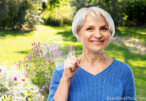 Image of smiling senior woman pointing finger up